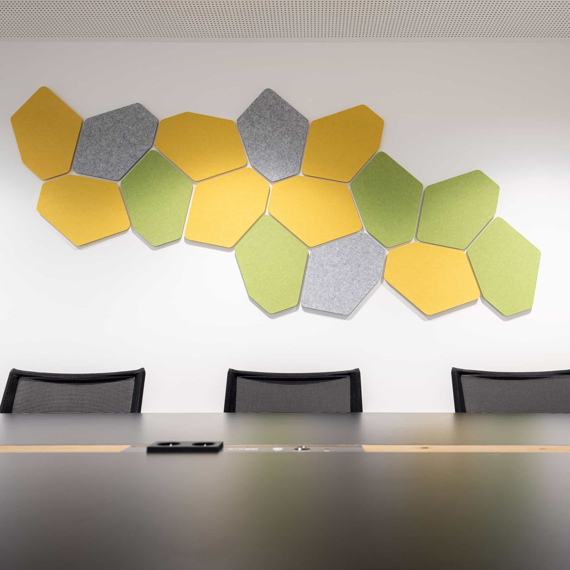 Yellow, grey and green acoustic wall panels above a conference table in a meeting room