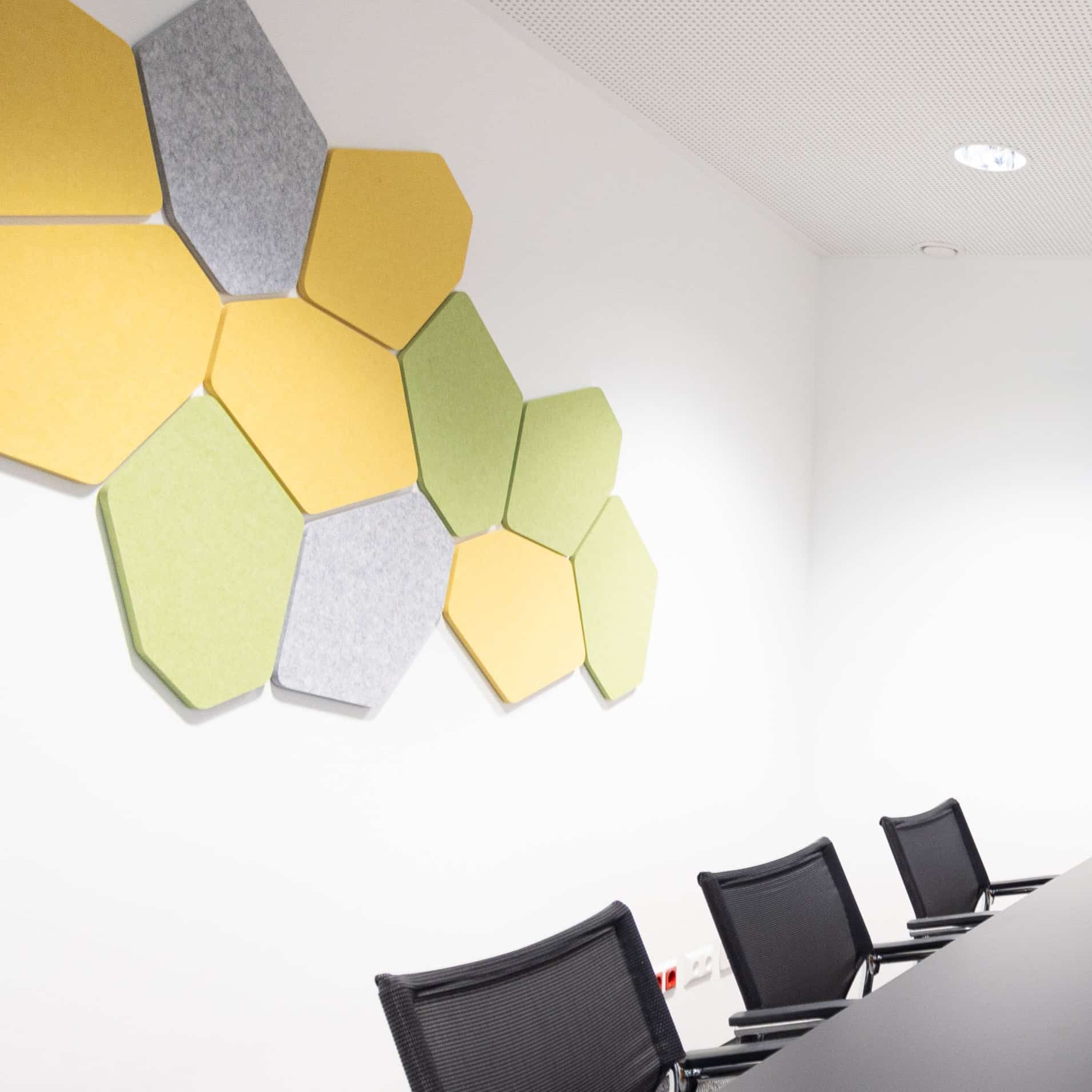 Close-up of hexagon acoustic panels in yellow, green and grey on a meeting room wall