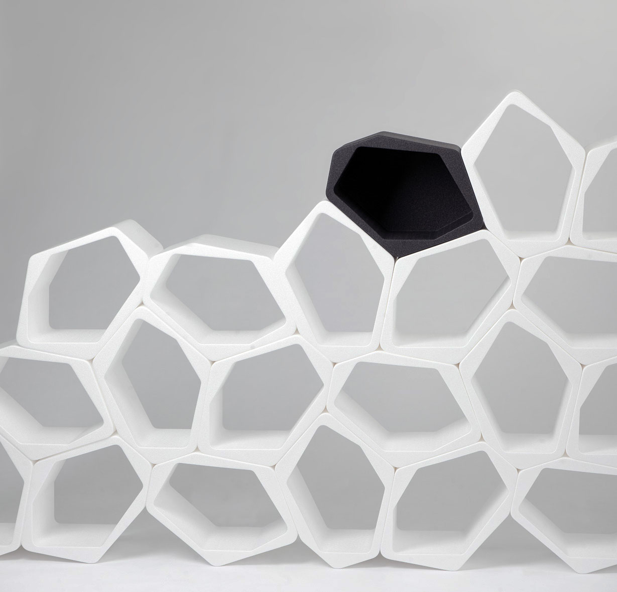 White modular honeycomb shelving units with one black unit