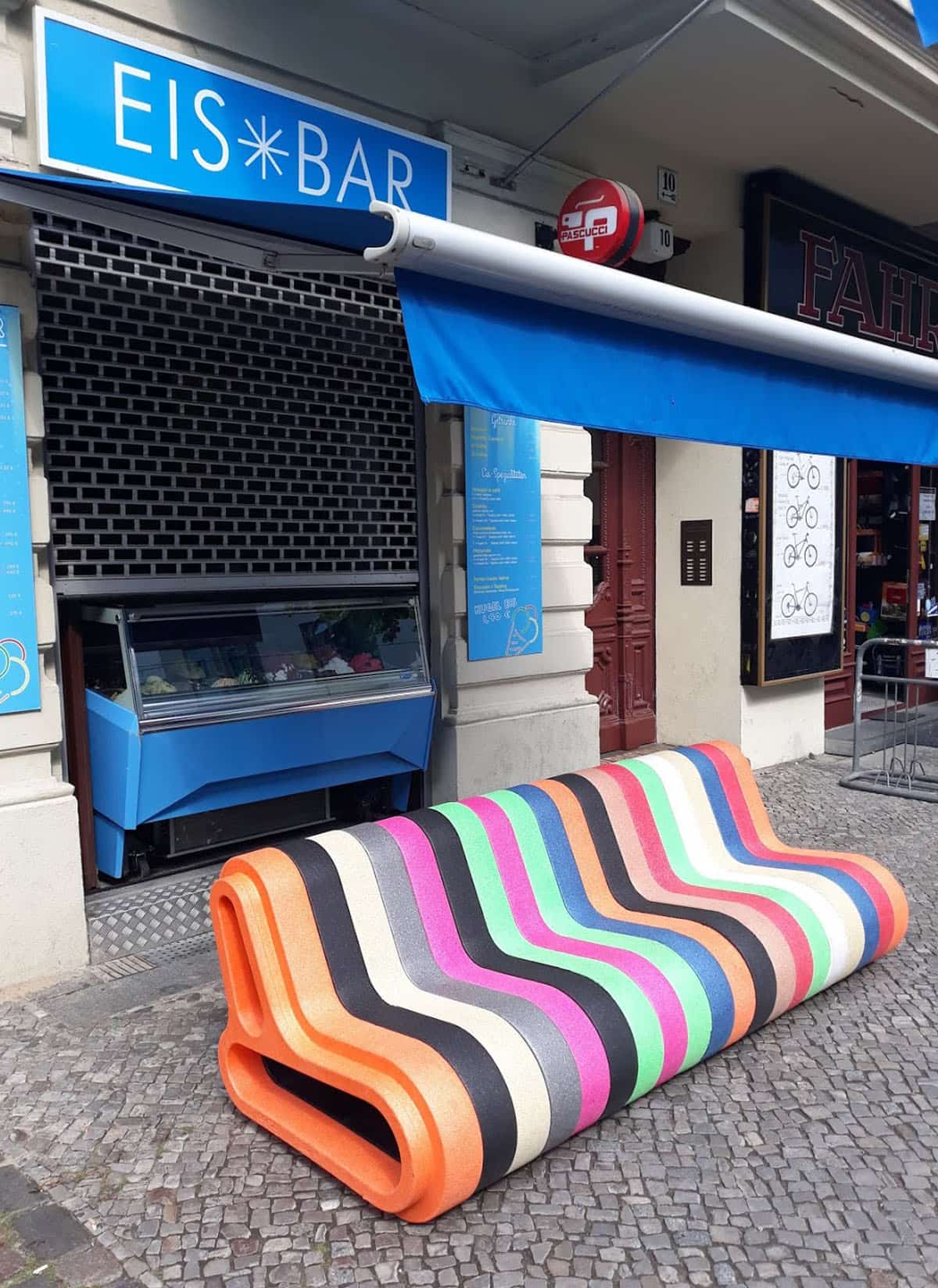 Long colourful striped Q-COUCH sofa in front of the Eis Bar in Berlin